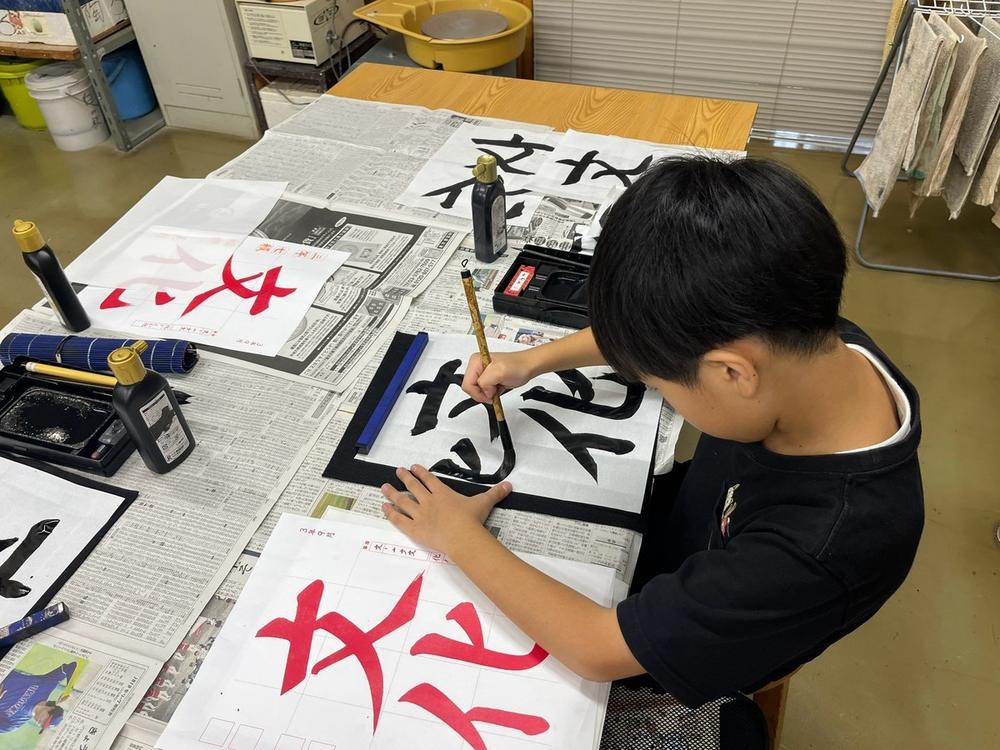 筆で「文化」と書くこども