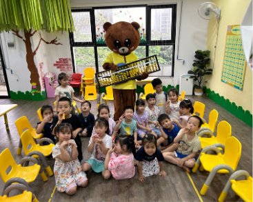 Kindergarten children with a bear holding a big soroban