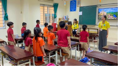 Students and a teacher standing in front of a classroom